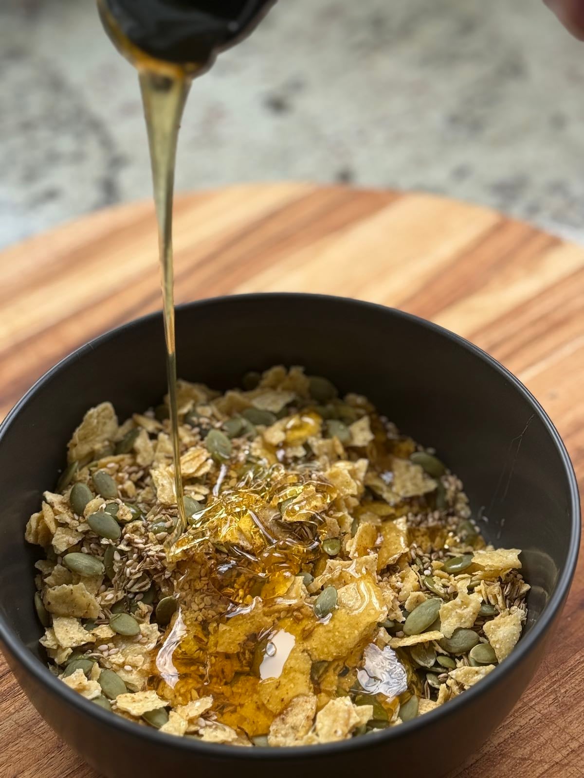 pouring honey into tortilla pepita mixture to create a sticky mixture.