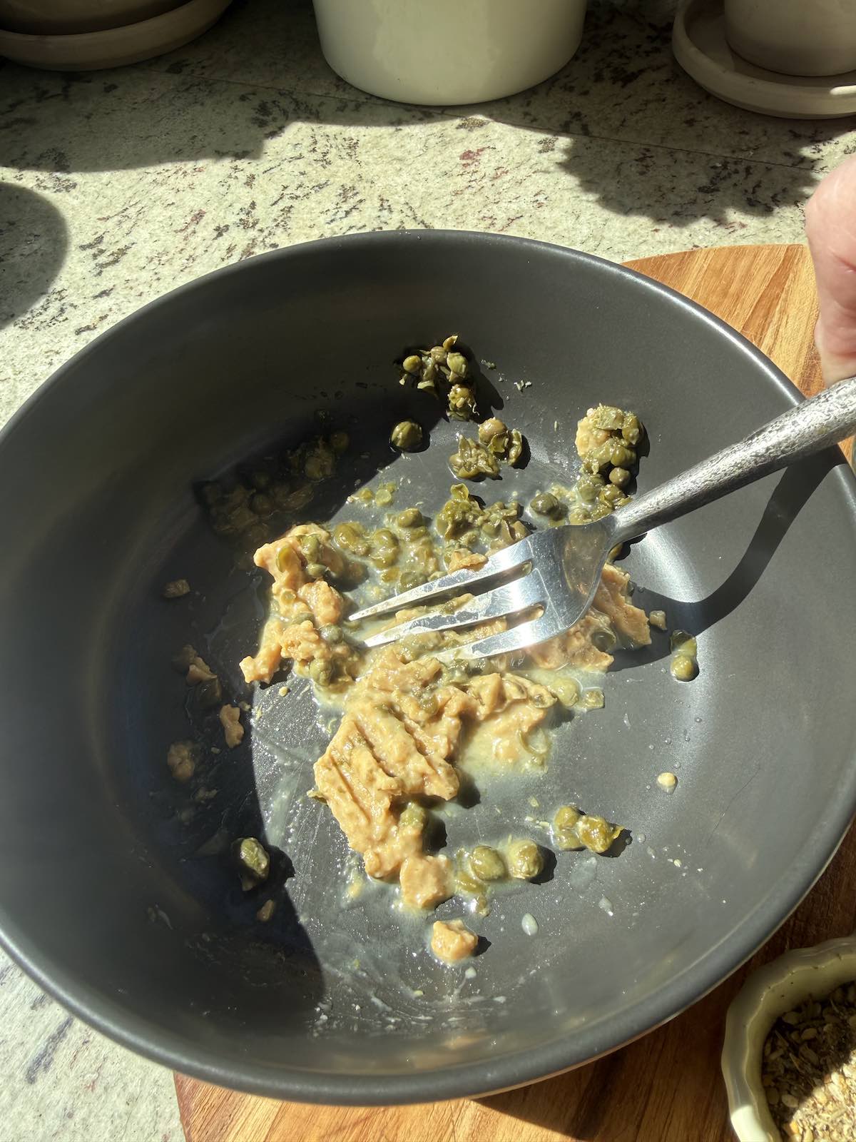 mashing the miso and capers into a paste in bowl.
