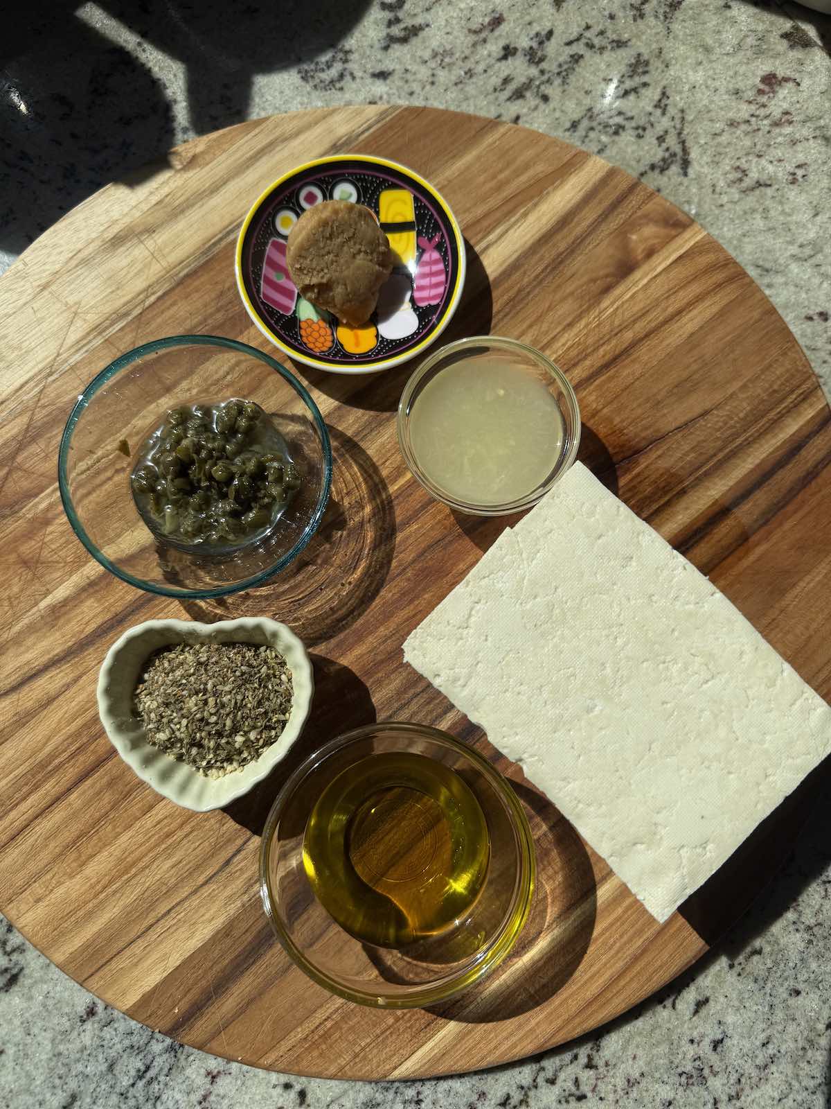 tofu marinade ingredients measure out alongside block of tofu on cutting board.