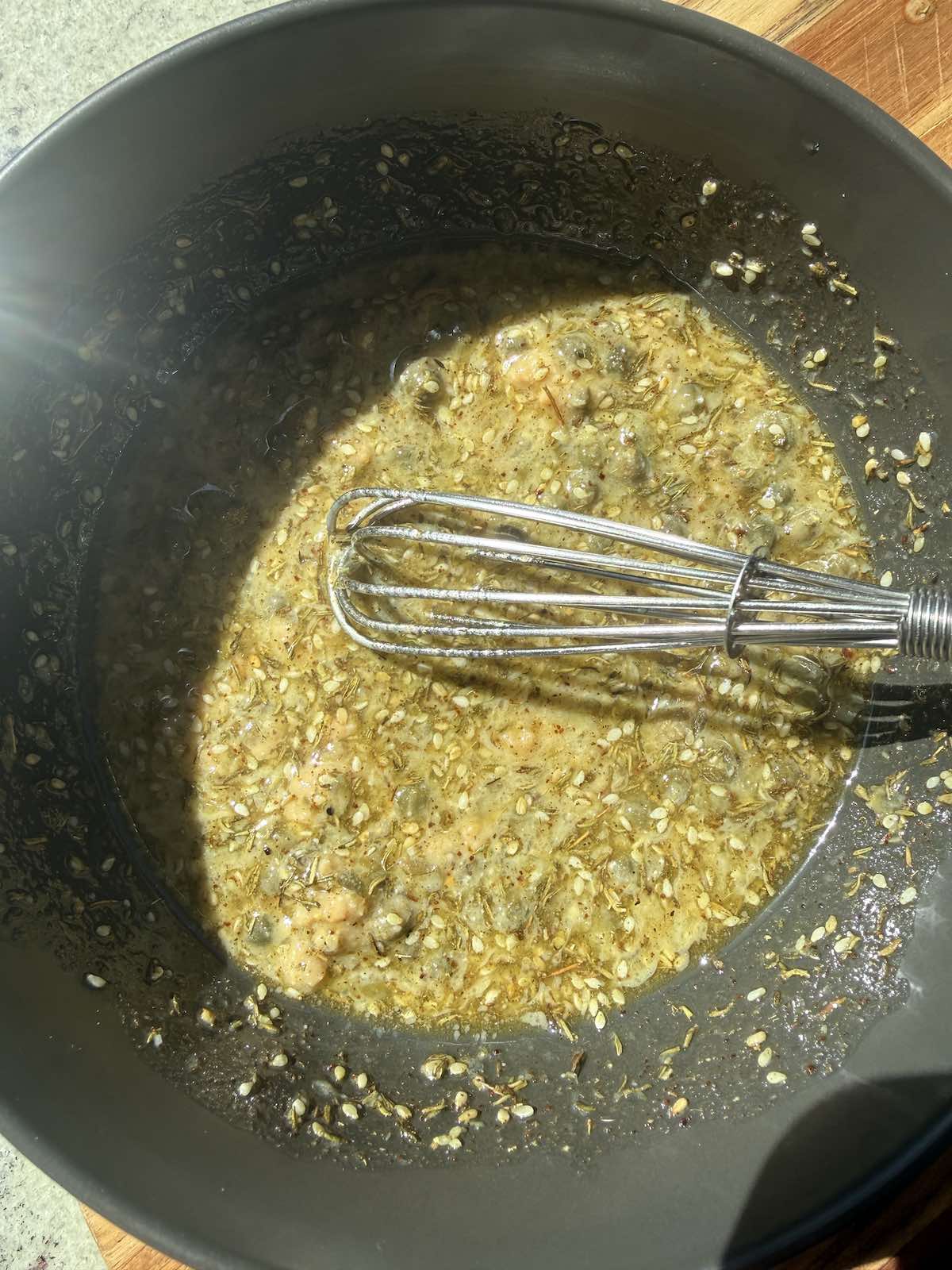 whisking all the marinade ingredients together in a bowl.