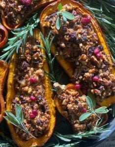 baked stuffed squash filled with tofu and veggies and garnished with pomegranate seeds and rosemary sprigs