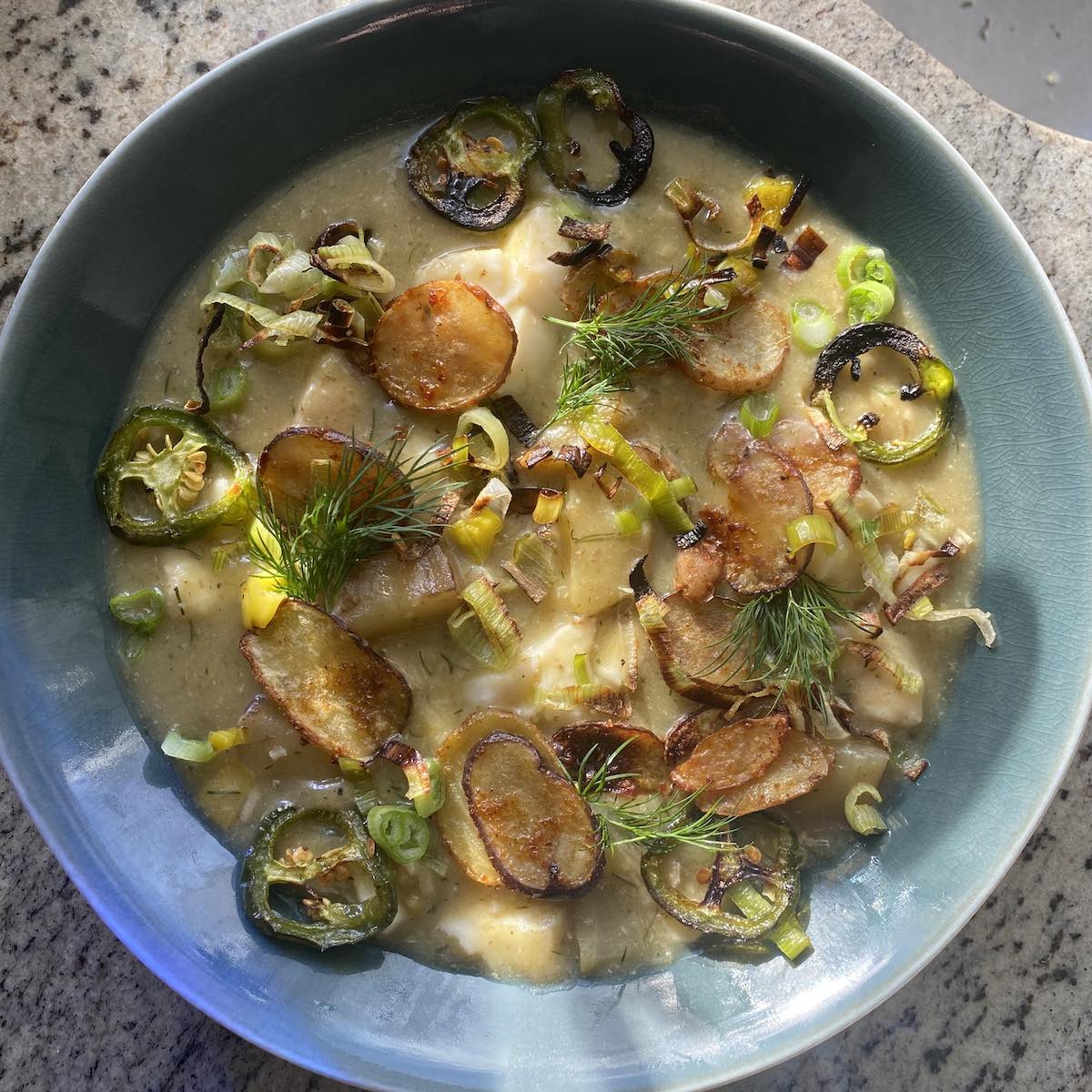 fish and potato stew served in bowl with toppings.