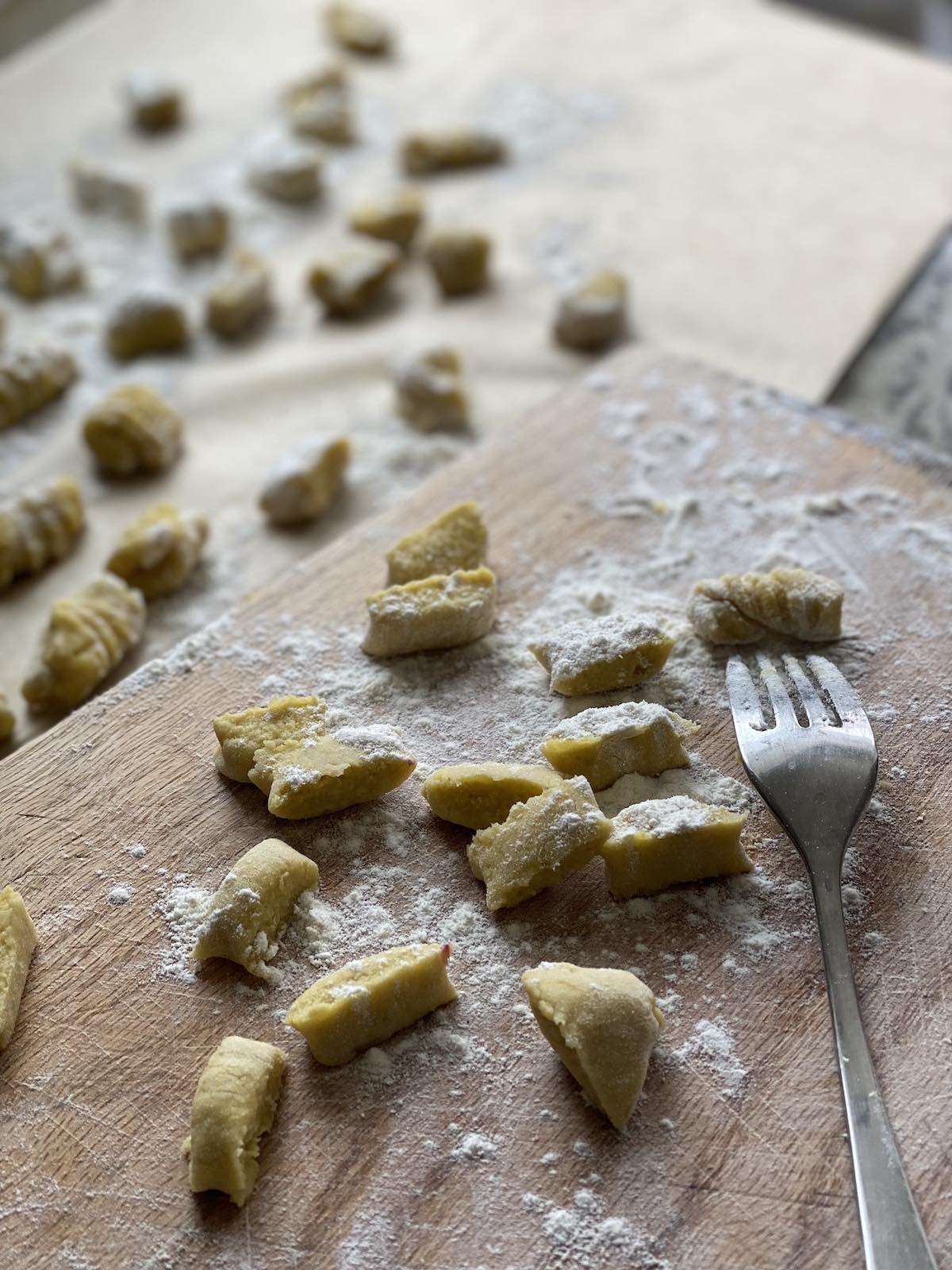 sweet potato gnocchi cut into small shapes and being formed over a fork into ridged shapes.
