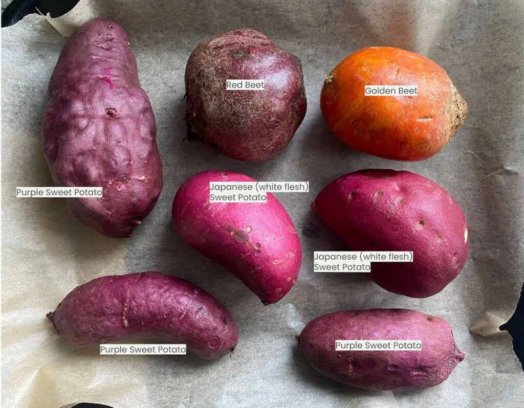 different types of beets and sweet potatoes, laying on sheet pan, whole and raw.