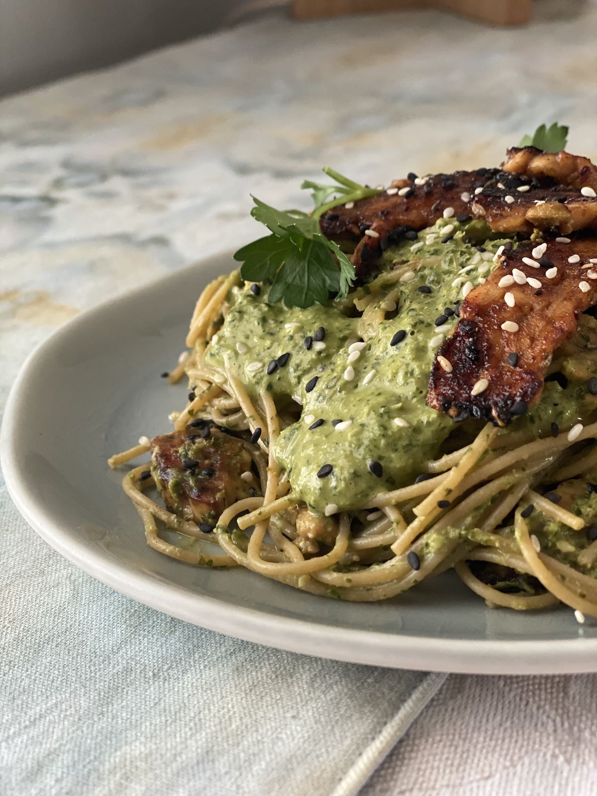 Side view of noodles, tahini sauce and tempeh.