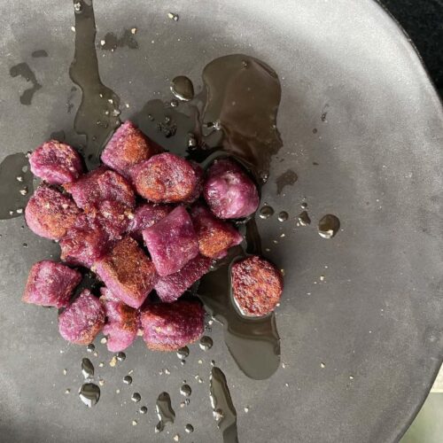 plate of pan-seared purple sweet potato gnocchi dressed with olive oil and smoked sea salt.
