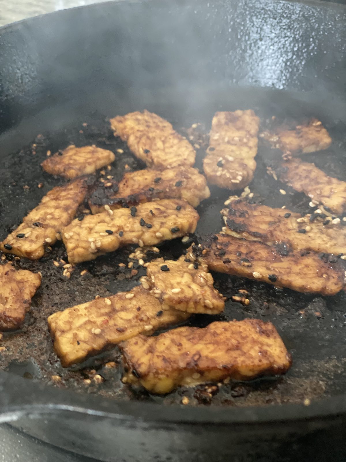 slabs of marinated tempeh searing in pan.