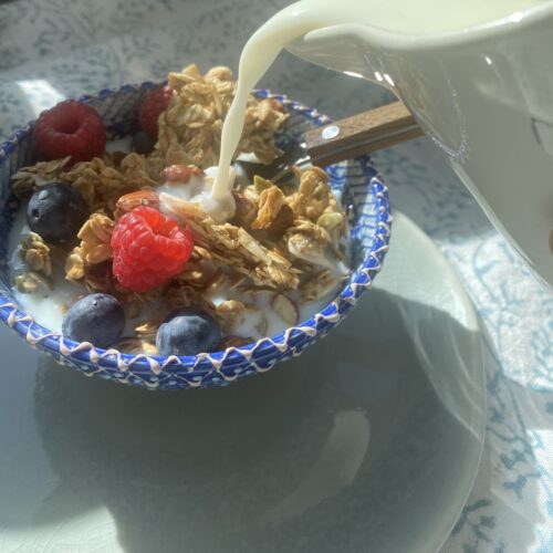 bowl of granola served with berries and milk.