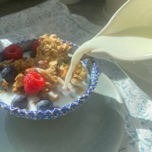 bowl of granola served with berries and milk.