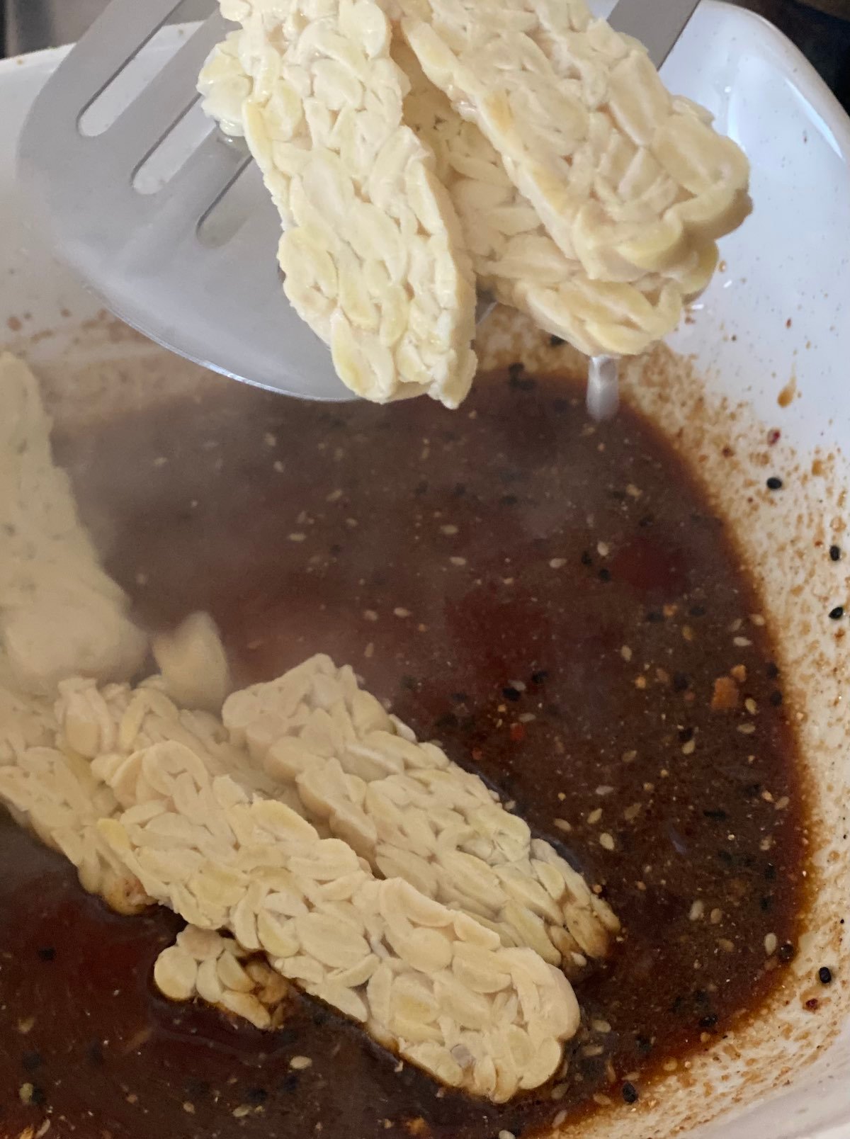 boiled slabs of tempeh being put into marinade.