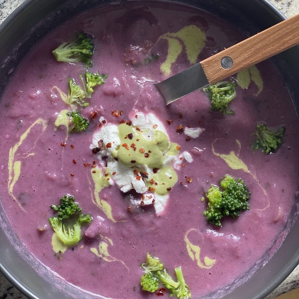 Bowl of purple sweet potato, broccoli and goat cheese soup.