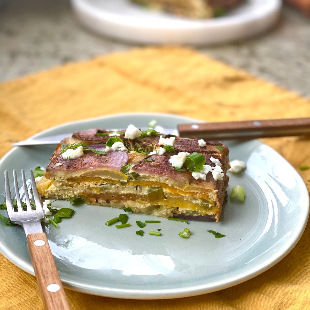 yellow squash, pepper, potato and ricotta layered bake, sliced on plate.