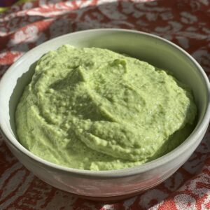 bowl of avocado crema with flecks of scallion and jalapeno.