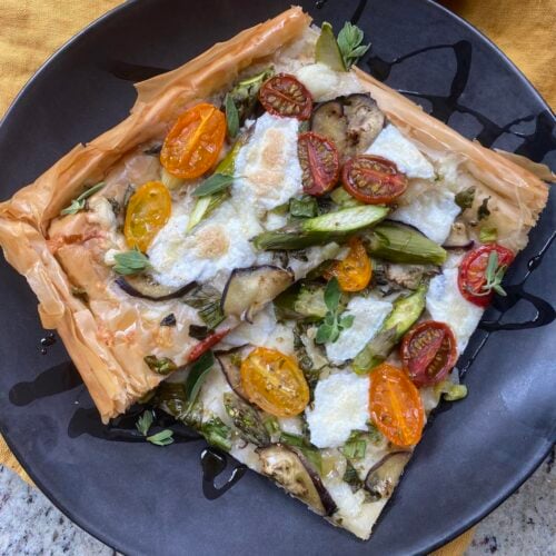 two slices of crispy sheet pan filo pizza on plate, with olive oil drizzled.