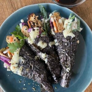 three tofu temaki sushi rolls, also known as hand rolls, on plate with side of tamari sauce.