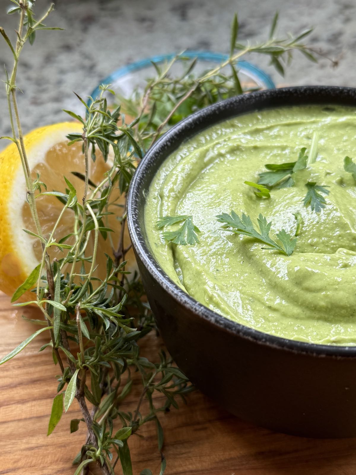 bowl of miso herb pesto with half a lemon and fresh herbs nearby.