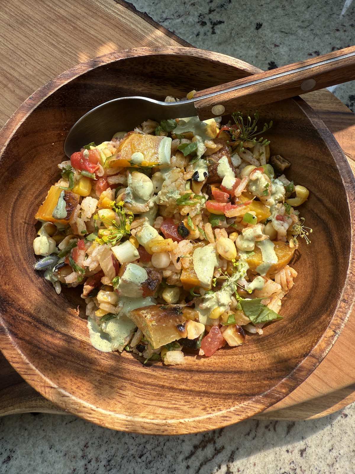 a single serving of spicy rice salad with roasted vegetables and cilantro lime drizzle.