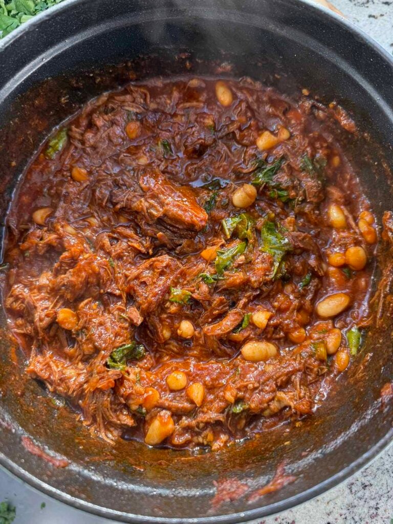 pot of beef ragu with greens and beans added.