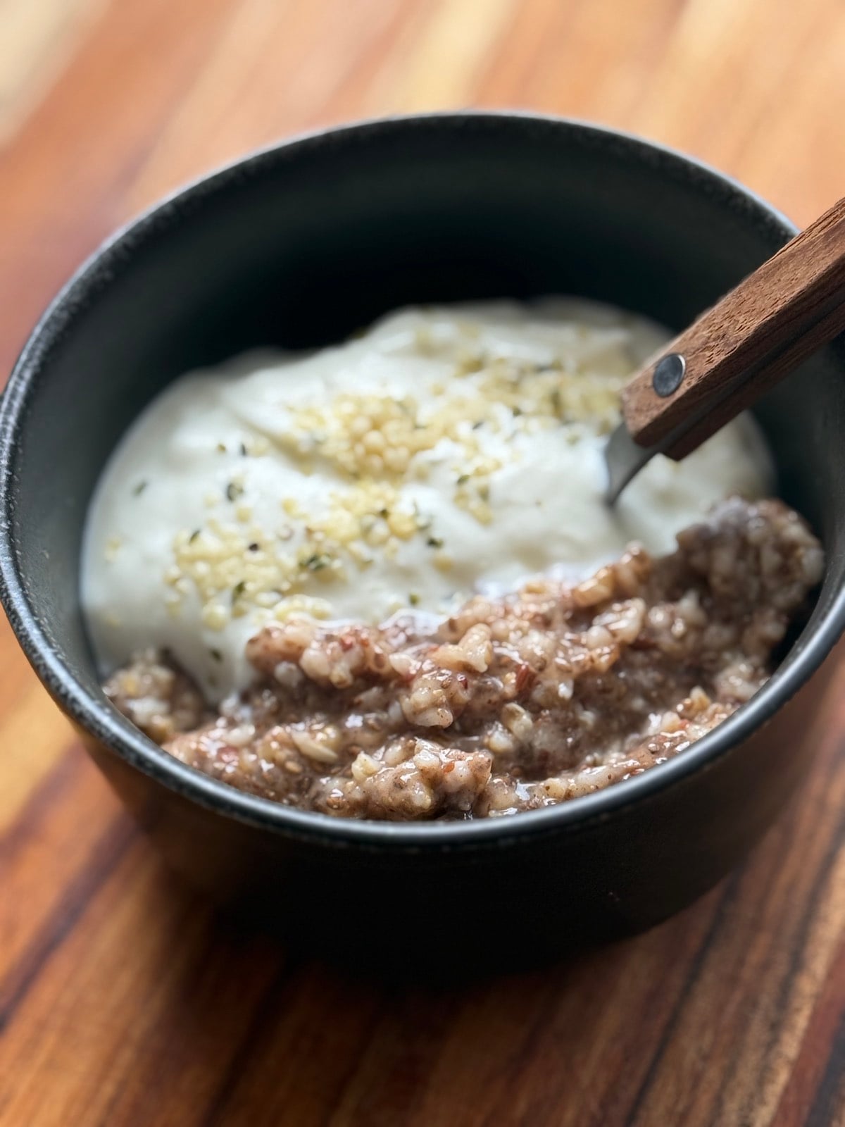 small bowl of steel cut oats cooked with chia and flax and served with yogurt and hemp seeds.