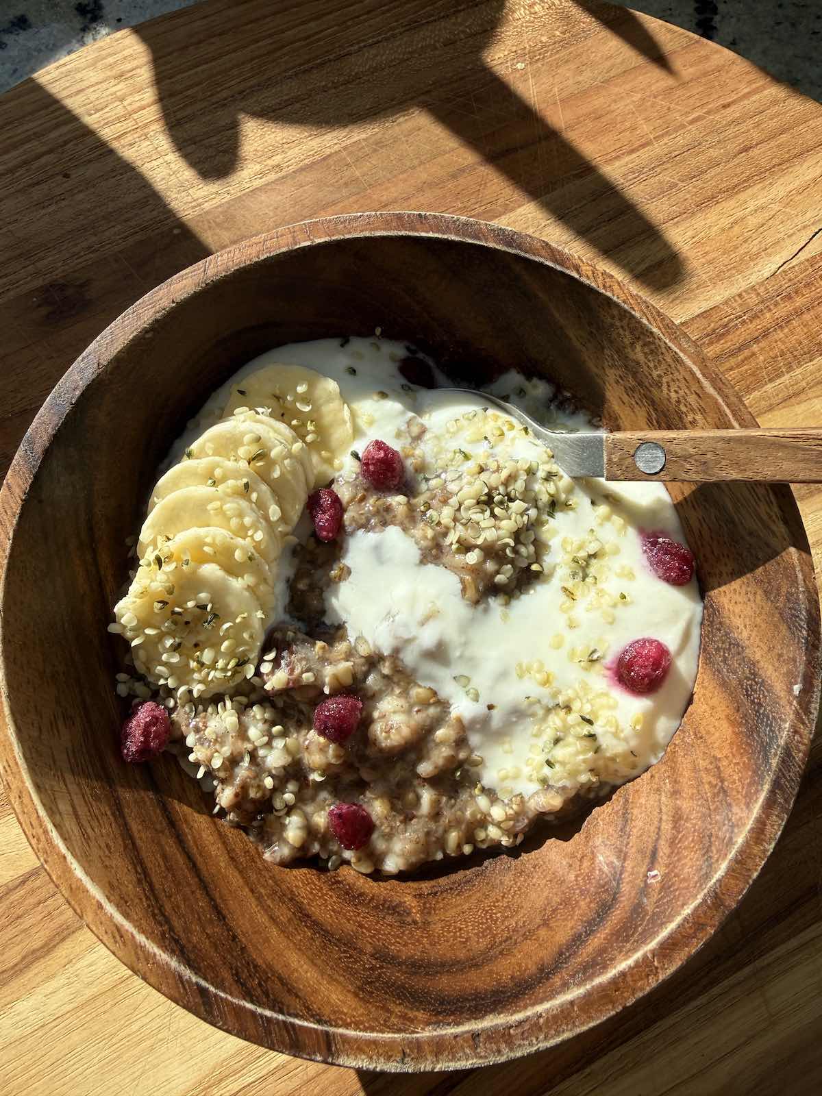 steel cut oats topped with yogurt, bananas and pomegranate arils.