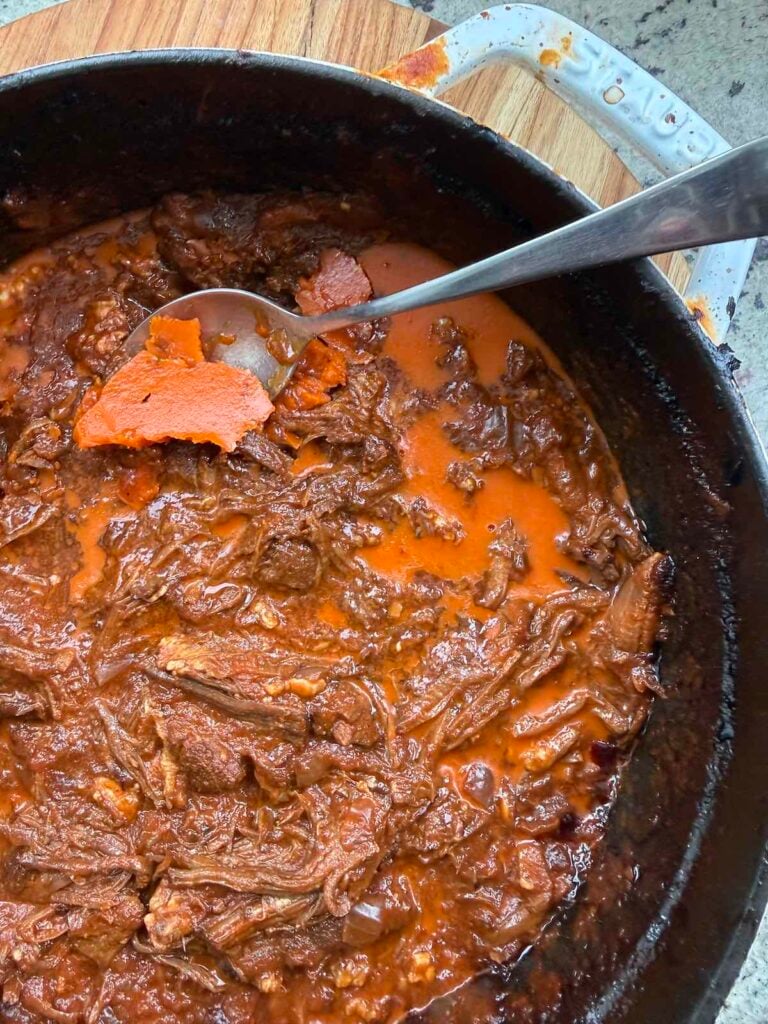 skimming fat from a pot of beef ragu, chilled overnight.