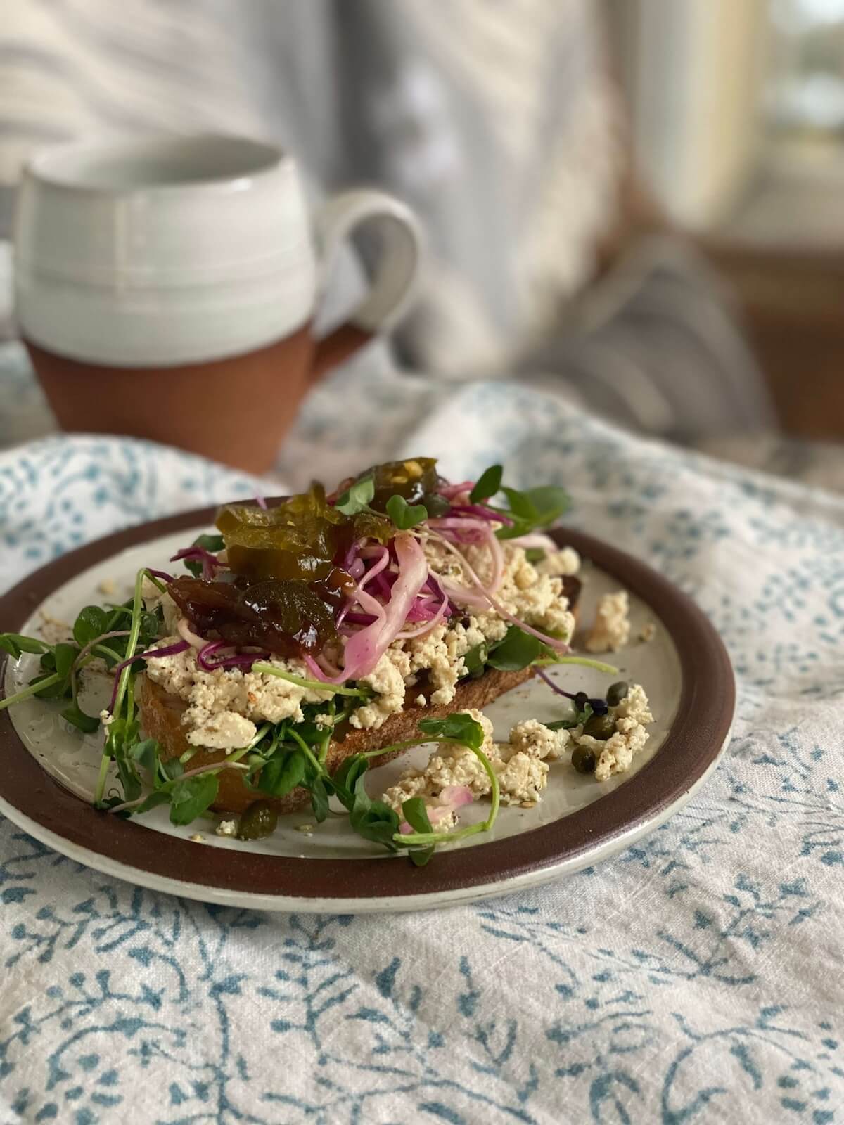 marinated tofu is crumbled as a topping on toast with pickled vegetables.