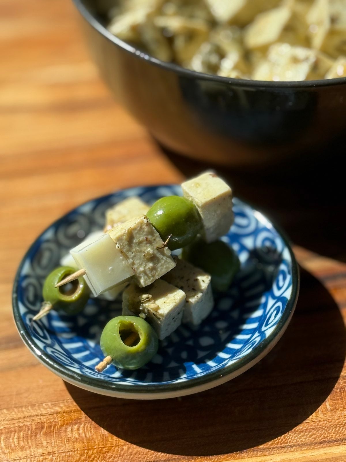 little appetizer bites of tofu, cheese, and olives on toothpicks.