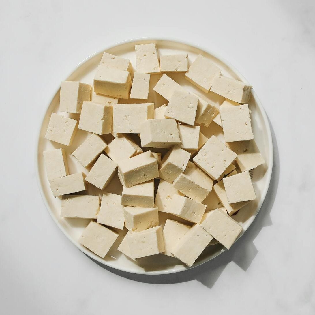 Top view of cubed tofu on a white plate, perfect for culinary projects