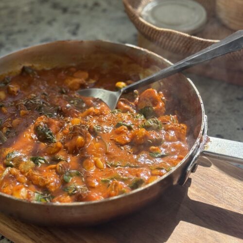 large saute pan with finished turkey curry with spinach and butter beans.