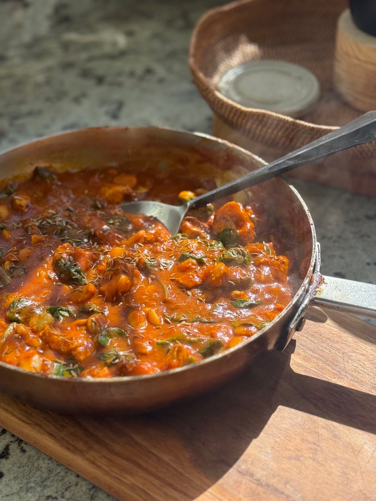 large saute pan with finished turkey curry with spinach and butter beans.