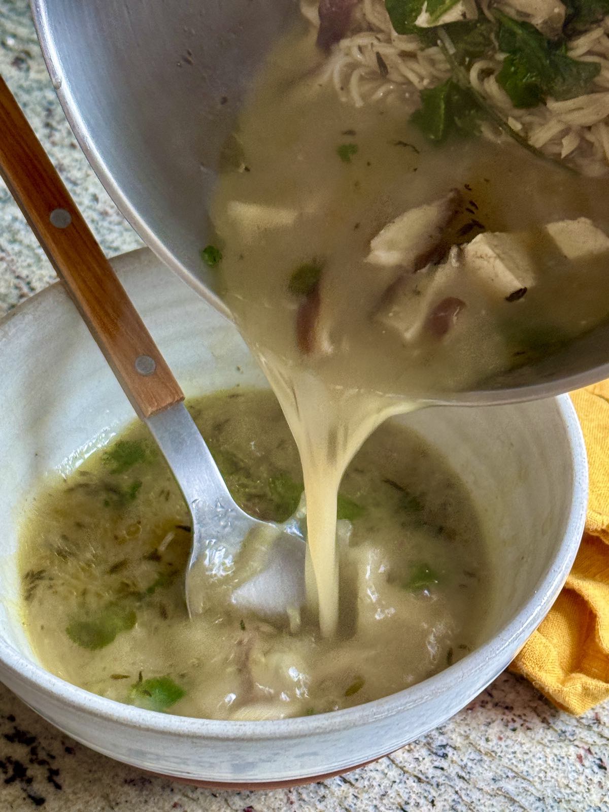pouring tofu miso soup into a bowl with a spoon.