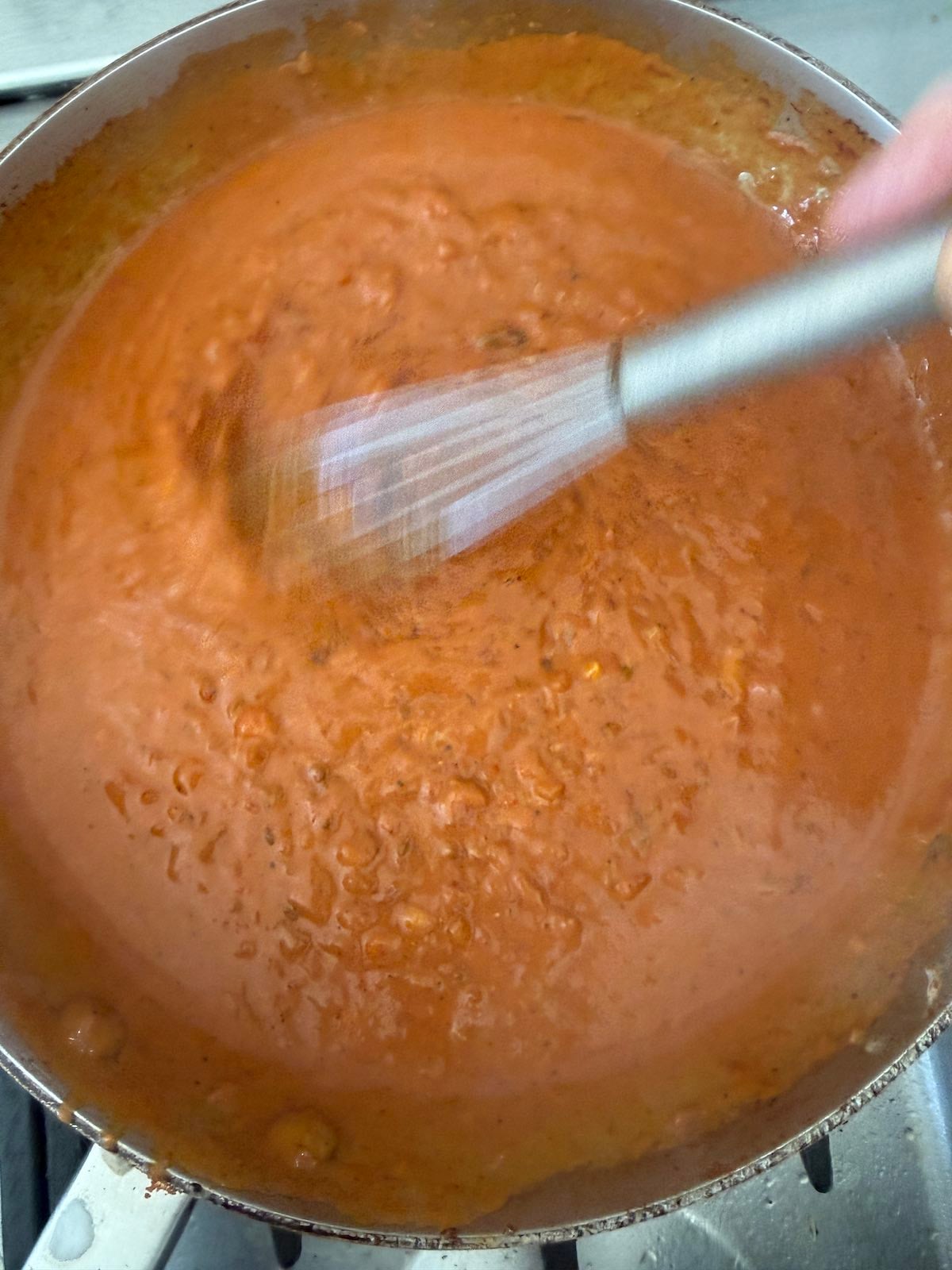 whisking coconut milk and water into tomato paste and sauteed onions.