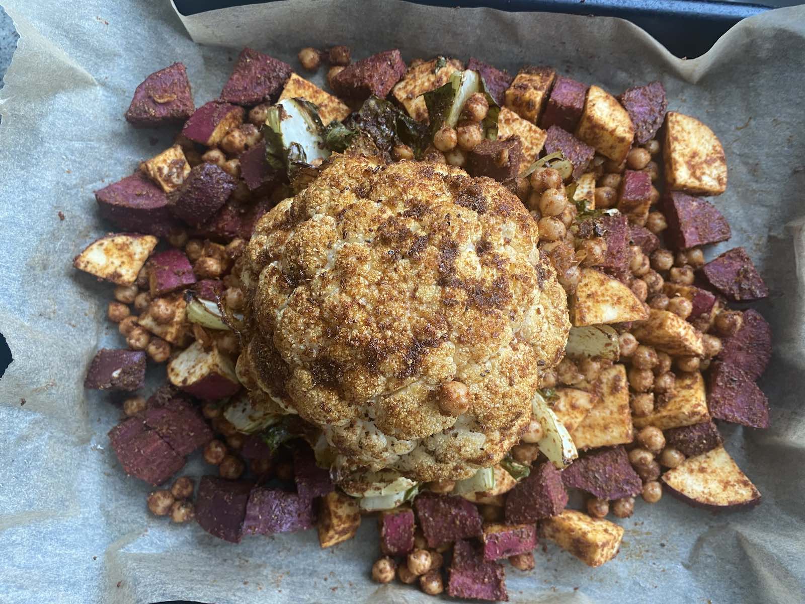 cauliflower on top of cubed sweet potato and chickpeas, on a sheet-pan, just out of oven roasting.