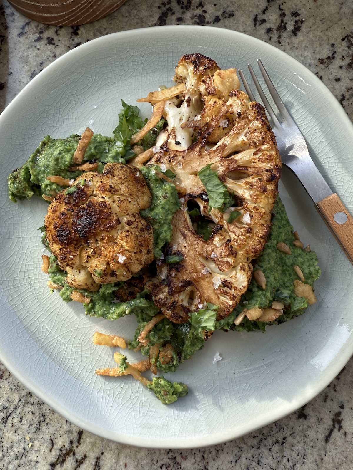 serving of harissa glazed cauliflower steaks over rapini and white bean puree.